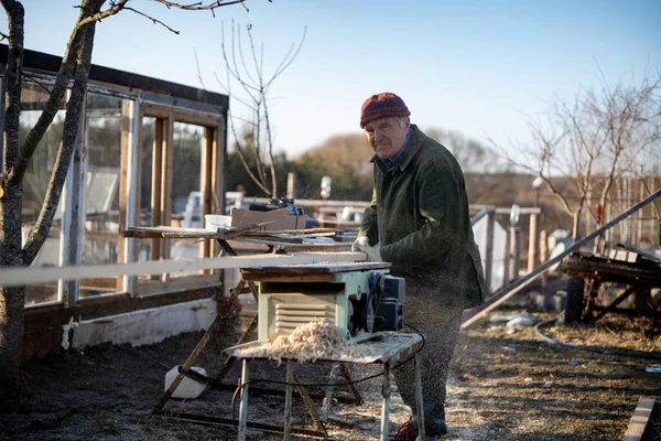 Dedem arka bahçedeki marangozluk makinesinde çalışıyor..