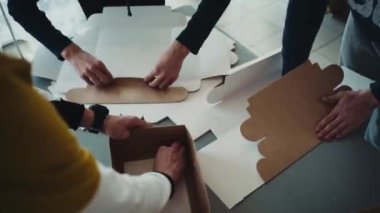 Bir grup genç bayram hediyesi olarak karton kutuları katlıyor, DIY, el yapımı, el yapımı