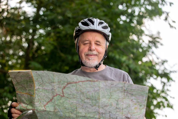 Senior man tittar på kartan under sin cykel eller cykling resa i skogen, hälsosam livsstil koncept — Stockfoto