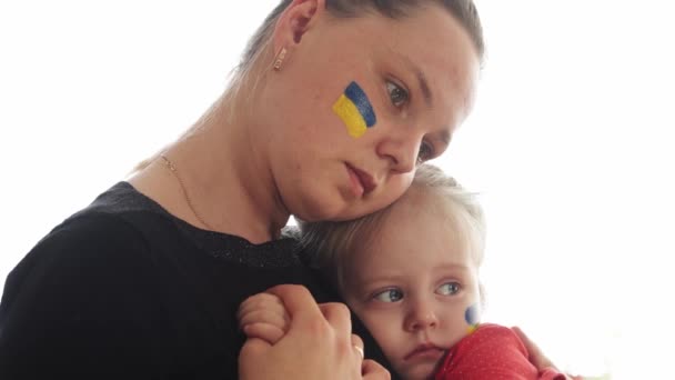 Mãe jovem ucraniana com filha com bandeira no rosto com medo de sofrer e rezar a paz durante o conflito de guerra entre a Rússia e a Ucrânia, invasão da Rússia na Ucrânia — Vídeo de Stock