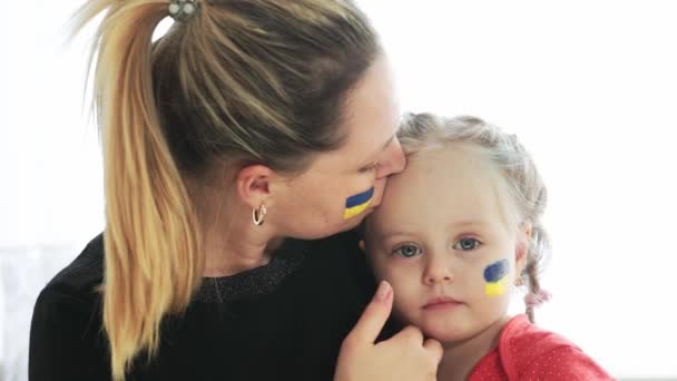 Madre joven ucraniana con hija con bandera en la cara con miedo, sufrimiento y oración de paz durante el conflicto de guerra entre Rusia y Ucrania, invasión de Rusia en Ucrania — Vídeo de stock