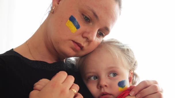 Madre joven ucraniana con hija con bandera en la cara con miedo, sufrimiento y oración de paz durante el conflicto de guerra entre Rusia y Ucrania, invasión de Rusia en Ucrania — Vídeos de Stock