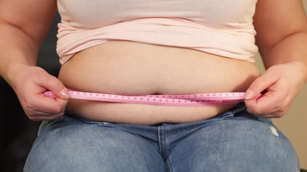Femeie tânără supraponderală sau plus dimensiune cu burtă grasă, mare care măsoară circumferința burții, viața oamenilor xl dimensiune, gros și conceptul de grăsime — Videoclip de stoc