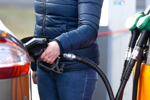 Высокие цены на бензин и дизельное топливо на АЗС, молодая женщина заправляющая автомобиль, концепция экономического кризиса — стоковое фото