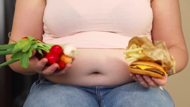 Junge übergewichtige oder übergewichtige Frau mit fettem, dickem Bauch und ungesundem und gesundem Essen Hamburger und gebratene Pommes und gesundes Gemüse, Leben eines Menschen xl Größe, dickes und fettes Konzept — Stockvideo