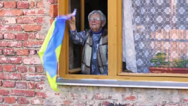 乌克兰祖母从窗户上挥动着乌克兰国旗，祈祷和平，祈祷俄罗斯2022年对乌克兰的侵略，为乌克兰增光 — 图库视频影像
