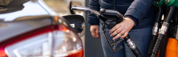 La mano operaia femminile che tiene l'olio di riempimento del combustibile dell'ugello nel serbatoio dell'automobile ad una stazione di servizio della pompa, per il concetto concetto di tecnologia di potere di trasporto di concetto — Foto Stock