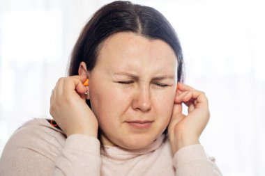 Genç bir kadının baş ağrısı, migren stresi ya da kulak çınlaması var. Kulaklarında çınlayan bir ses..