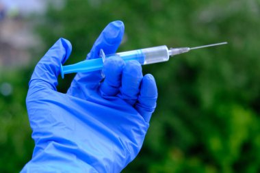 Yeşil arka planda şırıngalı bir el. Yaz zamanı.