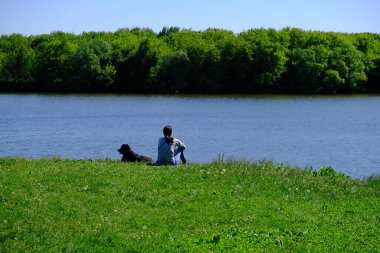 Suyun yanındaki tarlada köpeği olan bir kız.
