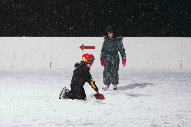 24.11.2021. Moskova 'da şiddetli kar yağışı var. Çocuklu insanlar Tsaritsyno parkı yakınlarındaki buz pateni pistinde