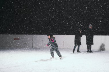 24.11.2021. Moskova 'da şiddetli kar yağışı var. Çocuklu insanlar Tsaritsyno parkı yakınlarındaki buz pateni pistinde