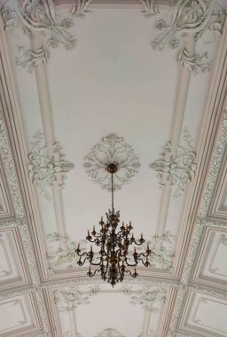 Yüzyıllık binanın yüksek tavanının altında eski bir avize.