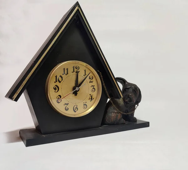 old vintage black table clock with a figurine of a dog on white background