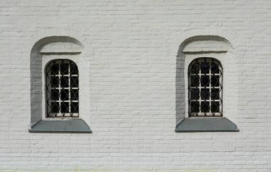 Eski bir tuğla binanın beyaz duvarının parçası. Geleneksel Rus mimarisi. Parmaklıklı iki pencere var. Geçmişi. Doku