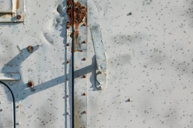 Kapısı olan eski gri metal bir duvar parçası. Vidalar da dahil. Paslı bölgeler ve su damlacıkları yüzeyde görülebilir. Geçmişi. Doku. 