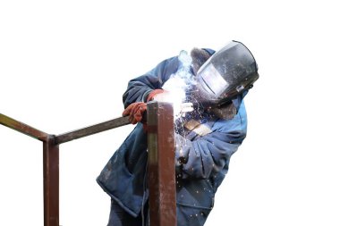 Mavi tulumlu ve koruyucu maskeli bir işçi metal elementleri elektrik kaynaklarıyla birbirine bağlar. Kıvılcımlar. Beyaz arkaplanda izole.                          