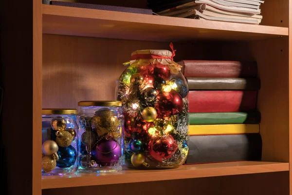 책장에는 색깔의 크리스마스 장식으로 유리병 화랑의 불빛이 타오르고 그라운드 — 스톡 사진