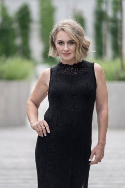 Beyaz, beyaz, beyaz, yetişkin bir kadının portresi. Siyah elbise giyiyor. Arka planda Bulanık Yeşil Çimen. İş Kadını.