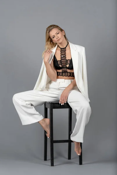 Portrait of Blonde Woman With White Jacket and Trousers. Isolated on Gray Background. Happy Face of Caucasian White Woman