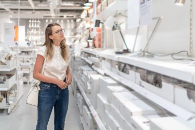 Güzel Beyaz Kafkasyalı Kız AVM 'de lamba arıyor. Bulanık Arkaplan.