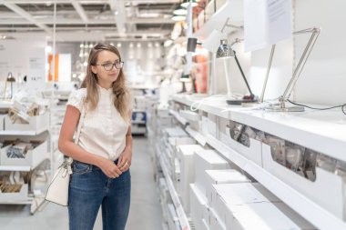 Güzel Beyaz Kafkasyalı Kız AVM 'de lamba arıyor. Bulanık Arkaplan.