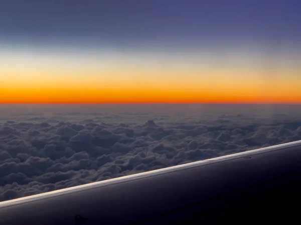Utsikt från planet på en del av vingen, flyger över ett tjockt lager av moln på natthimlen. Begreppet flygresor och transport. — Stockfoto