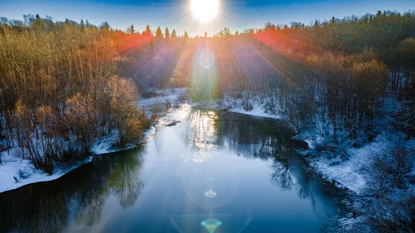 Drone view of a river with a lake on a snowy forest plain during a clear winter morning and bright sunrise — Stock Photo, Image
