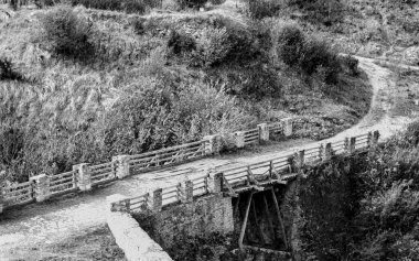 Black and white concept photo of an old wooden bridge crossing on a country road. High quality photo clipart