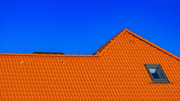 青い春の空を背景にオレンジの屋根のタイルと家の屋根の上のウィンドウ 高品質の写真 — ストック写真