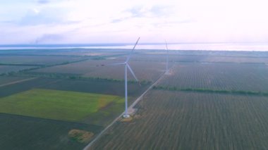 Sahildeki bir tarlada çalışan hava türbinlerinin hava görüntüsü.