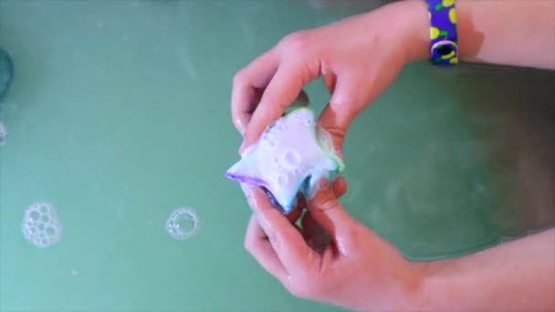 Vista superior de los corrales infantiles que juegan con una bomba de baño, disolviéndola en agua — Vídeo de stock