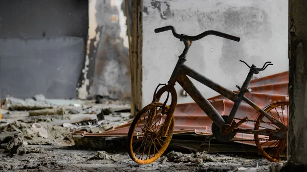 Irpin, Ukrayna - 22 Mayıs 2022: Rus birlikleri tarafından işgal edildikten sonra yıkılan bir evde yanmış bir çocuk bisikleti. Yüksek kalite fotoğraf.