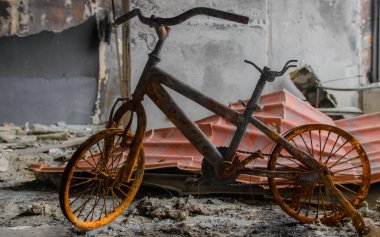 Irpin, Ukrayna - 22 Mayıs 2022: Rus birlikleri tarafından işgal edildikten sonra yıkılan bir evde yanmış bir çocuk bisikleti. Yüksek kalite fotoğraf.