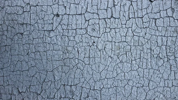 Cracks of old paint on a painted wall. Close up. Background, texture. High quality photo.