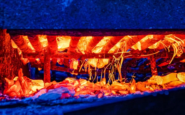 Barbecue grill and burning coals in the background, side view. Outdoor barbecue concept. High quality photo