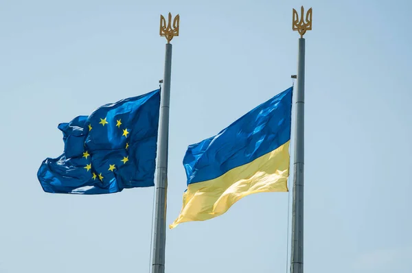 Ukrainska Och Europeiska Unionen Flagga Viftande Blå Himmel Med Vapensköld Stockbild