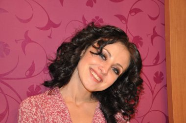 Kıvırcık saçlı, genç, pozitif bir kadının yüzü.