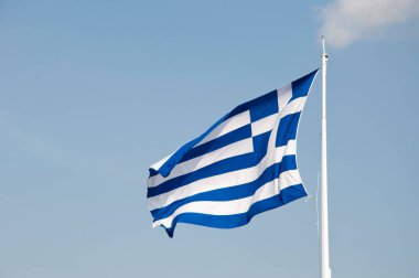 Yunan cumhuriyetinin ulusal bayrağı bayrak direğinin arka planında sallanıyor.