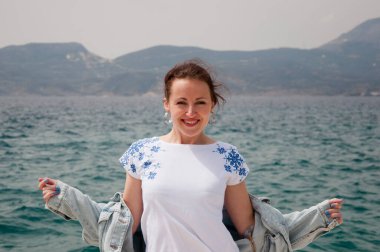 Yazın deniz manzaralı deniz manzarasına gülümseyen mutlu kız Ukrayna nakışı takıyor..