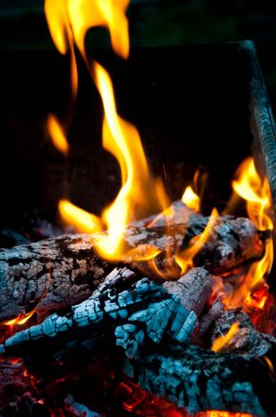 Flame of burning fire wood and smoldering charcoal close view abstract background.