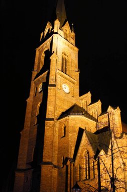 Almanya 'nın Guben şehrinde gece aydınlatması için saat kulesi olan Gotik katedral kilise yapısı..