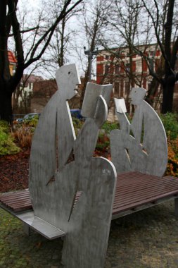 Açık hava parkı ahşap bankı çelik adam heykelleriyle süslenmiş kitap okuyan..