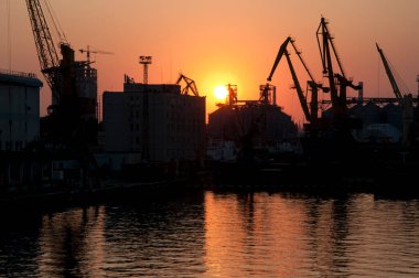 Odesa sea port container crane silhouettes at sunset sky background.