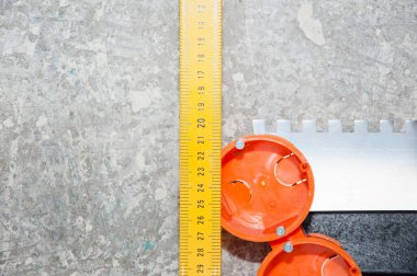 Çimento arkaplanı üzerinde sarı metal cetvel ve spatula yenileme araçları, boşluğu kopyala.