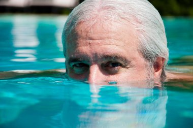 Grimsi bir adam gözleriyle suya bakar. Bakıyorum, bakıyorum. Adam gözleriyle bakıyor..