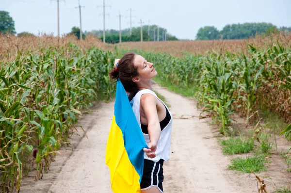 free ukraine woman in field with ukrainian flag.