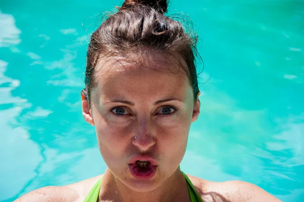 woman with funny wet face at summer swimming pool.