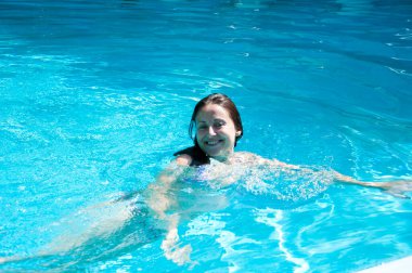 Tatilde havuzda yüzen mutlu kadın..