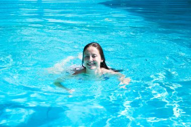 glad girl swimming in summer pool water on vacation.
